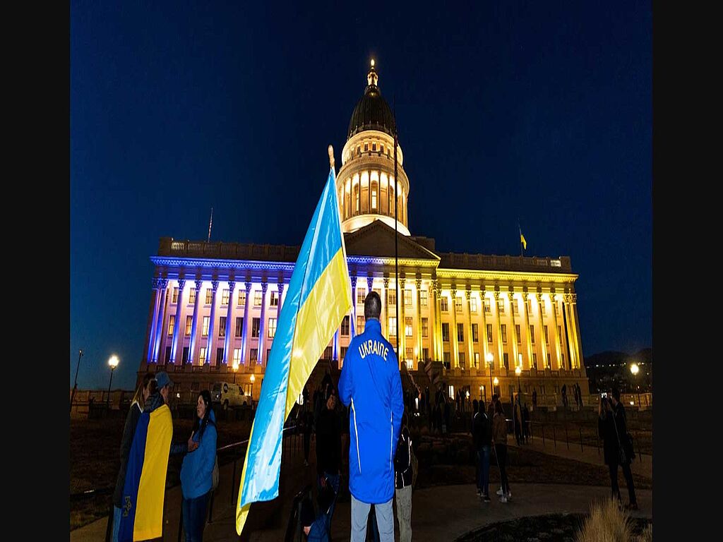 Zac Haycock se tient devant le Capitole, qui est éclairé en bleu et jaune en soutien à l'Ukraine.