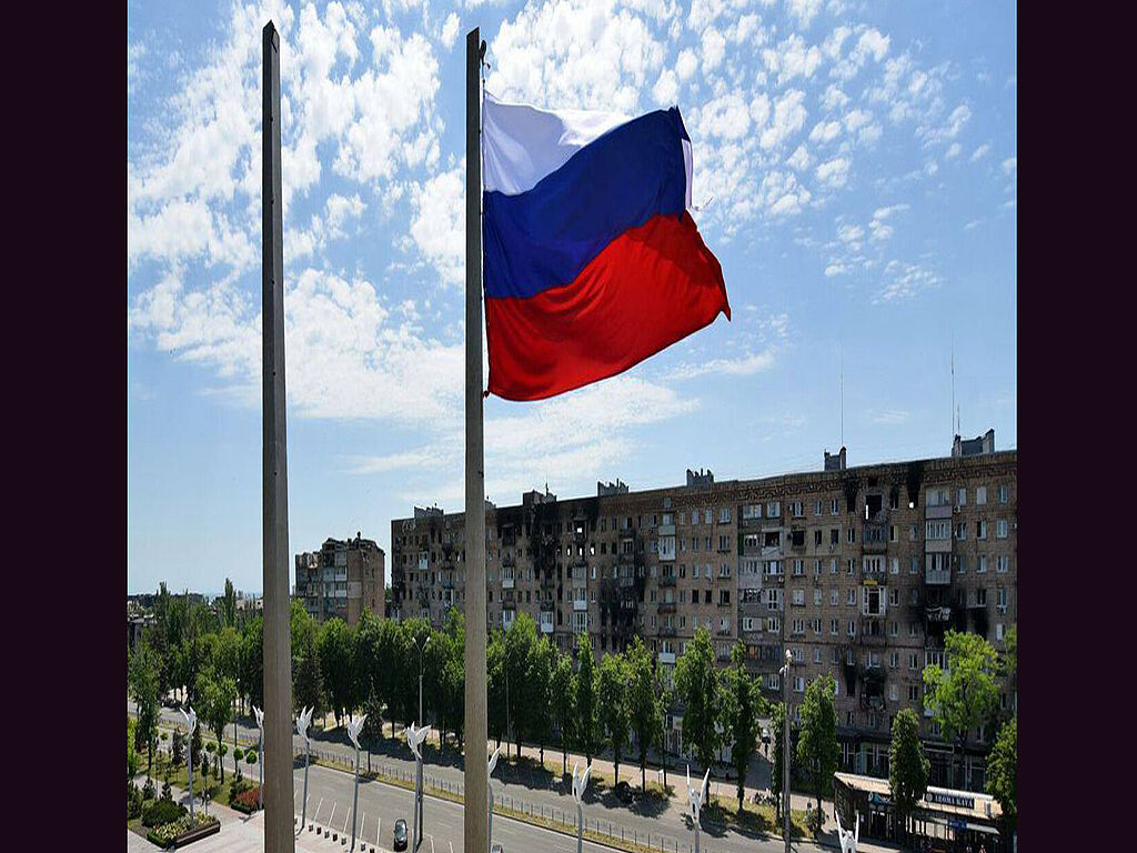 Un drapeau russe sur le fond d'un bâtiment détruit, symbolisant la Russie. La place de la Liberté a été rebaptisée place Lénine par les occupants russes parce qu'il n'y a pas de libertés en Russie