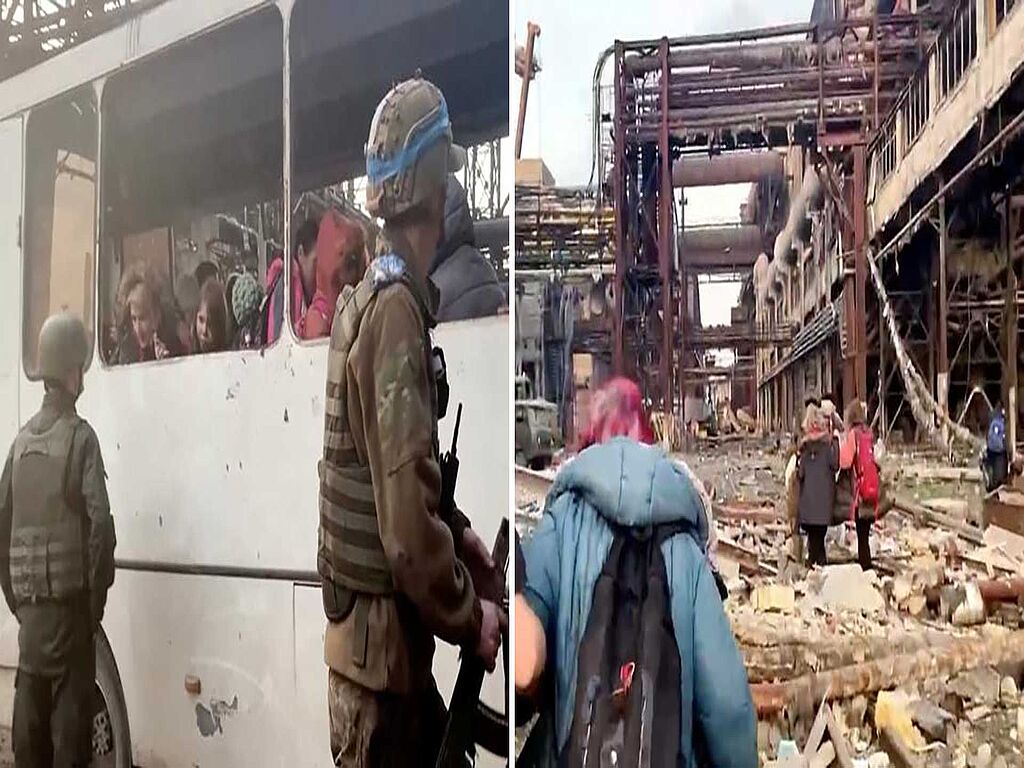 Azov regiment members stand as civilians board a bus at the Azovstal steel plant during UN-led evacuations