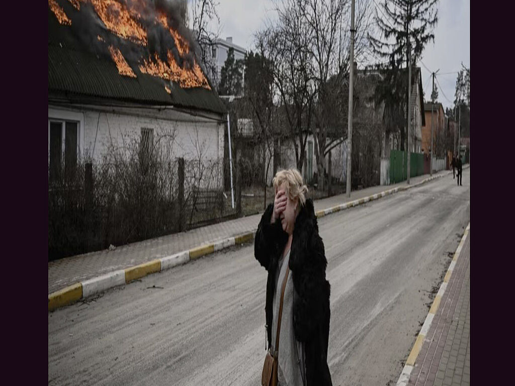 A Ukrainian woman cries near her burnt house