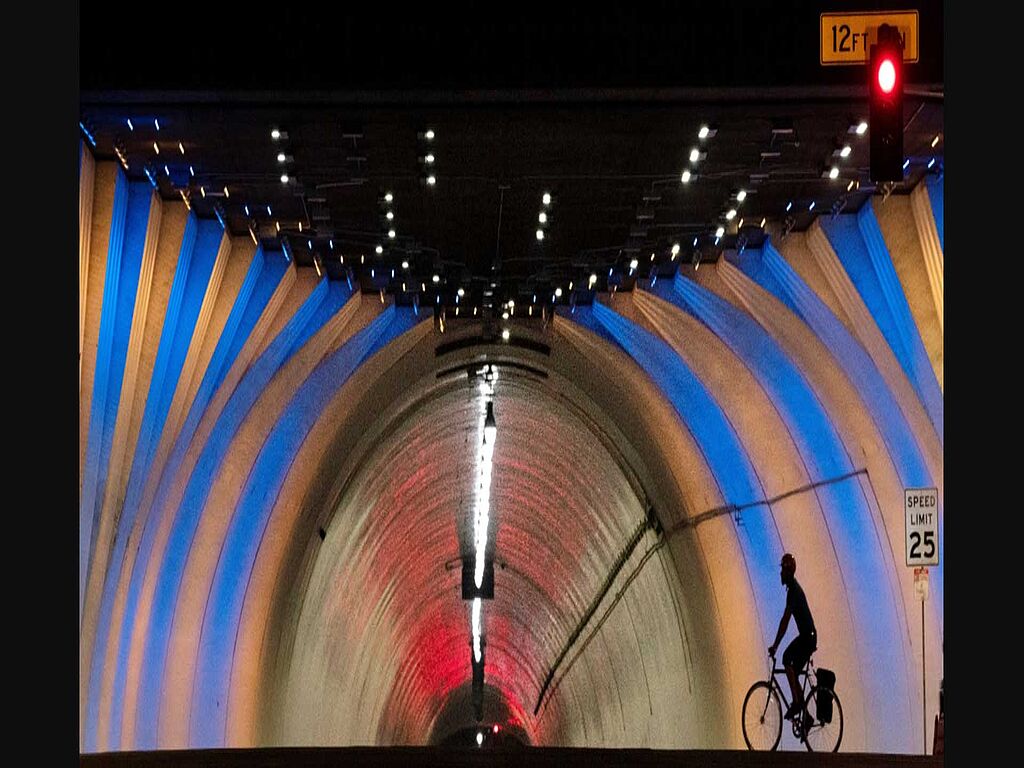 Un cycliste passe devant le célèbre tunnel de la 2e rue, illuminé aux couleurs du drapeau ukrainien.